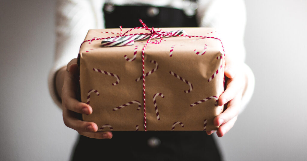 Woman extending holiday wrapped gift