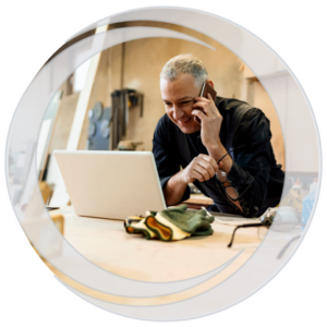 Eastern Savings Bank Business Banking. Business man in workshop on phone in front of laptop